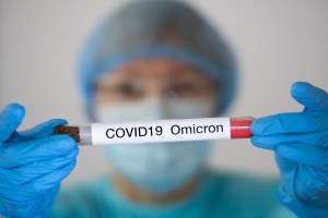Frau in Schutzanzug und Gesichtsmaske hält ein Reagenzglas mit einer Analyseprobe, die vermutlich mit der Omicron-Coronavirusvariante COVID-19 2019-nCoV infiziert ist. Konzeptfoto. Foto-Illustration. (Foto von Maxym Marusenko/NurPhoto)