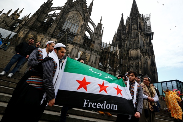 מהגרים מסוריה מחזיקים בדגל שלהם מחוץ לקתדרלה בגרמניה, צילום: רויטרס